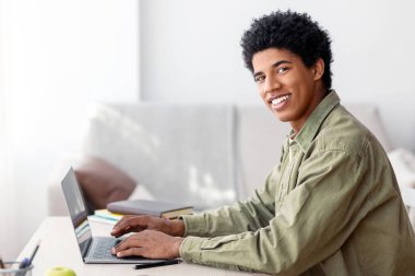 E-öğrenme konsepti. Evde dizüstü bilgisayar dersi alan Afrikalı Amerikalı bir gencin portresi, boş yer. Çevrimiçi konferansa katılan pozitif siyahi gençler ya da İnternet 'te öğretmenle konuşan