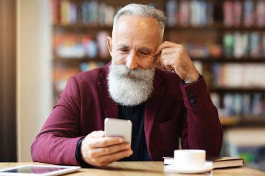 Uzun sakallı, kafeteryada kahve içen, akıllı telefon kullanan, gününü planlayan, fotokopi çeken yaşlı gri saçlı adam. Kahve molası veren, elinde cep telefonu tutan yakışıklı bir iş adamı.
