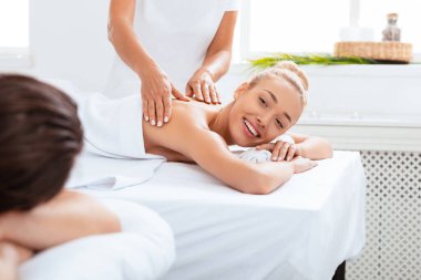 Eş, masaj sırasında kocasına gülümsüyor. Güzellik salonundaki yataklarda uzanırken rahatlıyor ve prosedürden zevk alıyor. Rahatlama Terapisi, Gençleştirme ve Sağlık Konsepti. Seçici Odaklanma