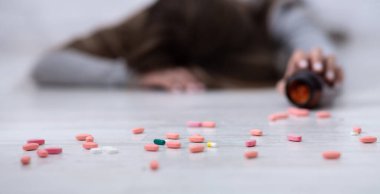 İntihar eden genç bir kadın, kavanozdan yayılmış tabletlerle yerde yatıyor, seçici bir odak noktası. Depresyon ve uyuşturucu aşırı kullanımı, akıl hastalığı veya psikolojik bozukluk kavramı