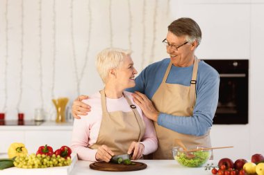 Mutlu Son Sınıflar Yemek Pişiriyor ve Kucaklıyor Akşam Yemeği İçin Vejetaryen Salatası Yapıyor Modern Mutfakta Bekliyor. Hafta sonları evde birlikte yemek hazırlayan yaşlı çift. Sağlıklı Beslenme Konsepti