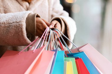 Alışveriş konsepti zamanı. Bir sürü renkli çanta taşıyan ve alışveriş merkezinin yakınında yürüyen tanınmayan siyahi kadın müşterinin yakın çekimi. Alış veriş ve hediye taşıyan Afrikalı Amerikalı bir kadın. Perakende ve Satış