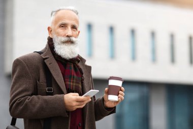 Yakışıklı, gri saçlı, elinde kahve bardağıyla gezen ve modern akıllı telefon kullanan teneffüste sokakta yürüyen, fotokopi çeken bir adam. Yaşlı adam işe gidiyor, sabah kahvesini içiyor.