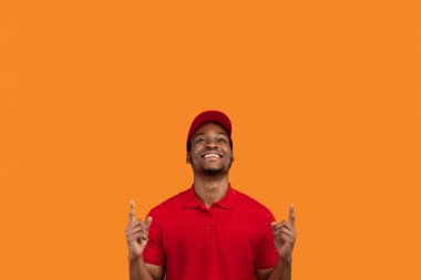 İyimser Afro-Amerikan dağıtım elemanının portresi. Kırmızı tişörtlü, şapkalı, gülümseyen, bakan ve parmaklarını fotokopi makinesinin arka planında izole edilmiş.