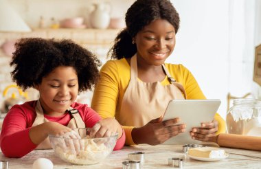 Neşeli Siyah Anne ve Sevimli Küçük Çocuk Mutfakta Dijital Tablet Kullanıyor, Kurabiye Tarifi İnternette, Afro-Amerikan Ailesi Ev Yapımı Pastayı Hazırlıyor, Yakın Çekim