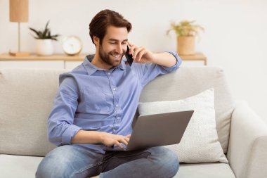 Modern ofiste koltukta oturan bilgisayarın başında cep telefonuyla konuşan mutlu adam. Kapalı alanda çalışan serbest çalışan adam telefonla konuşuyor. Serbest, Mobil İletişim Konsepti