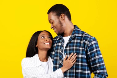 Hassas bir an, genç romantik bir çift eğleniyor, evli insanlar randevularında eğleniyor. Mutlu Afro-Amerikalı erkek ve bayan sarılıp birbirlerine bakıyorlar, sarı arka planda izole edilmiş, stüdyo çekimi, serbest alan