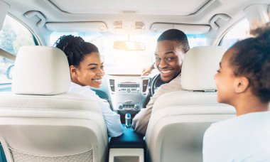 Hafta sonundaki yaz gezisi sırasında üç kişilik mutlu siyah aile gezisi. Neşeli Ebeveynler ve Kızı Yeni Otomobillere Biniyor. Araba Satışı ve Satın Alma Konsepti. Seçici Odaklanma, Geri Görünüm