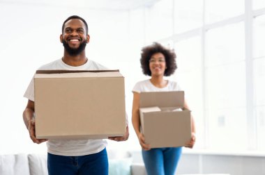 Yeni ev. Afrika kökenli Amerikalı Çift Taşındıktan sonra Karton Kutuları Taşıyarak Taşınıyor. Gayrimenkul kavramı. Genç Aile Konutları, Mülkiyet ve Satın Alım