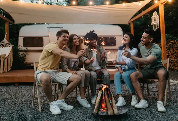 Milenyum çeşitliliği olan arkadaşlar, yanan maytaplarla şenlik ateşinin yanında oturuyor, eğleniyor, kamp gezisinde birlikte bir şeyler kutluyor, karavanda seyahat ediyor, dışarıda dostça sohbetin tadını çıkarıyorlar.