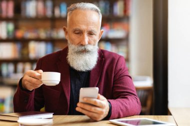 Kahvesini içip cep telefonu kullanan, e-postalarını kontrol eden ya da müşterileriyle sohbet eden, kafede tek başına dinlenen, kahverengi ceketli yaşlı bir adam. Yaşlılar ve aletler konsepti