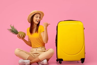 Bavulu işaret eden ananaslı bir kız egzotik ülkelere tatile gidiyor, pembe bir geçmişi var.