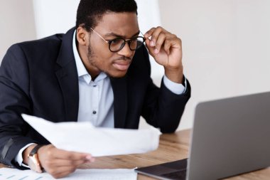Gözlüklü muhasebeci elinde kağıtlar olan siyahi bir adam, ofisinde dizüstü bilgisayar kullanıyor, raporları kontrol ediyor, fotokopi çekiyor. Afrika kökenli Amerikalı menajerin görüş sorunu var. Ekrana bakarken gözlüğünü çıkartıyor.