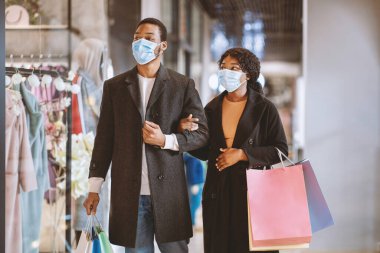 Satış, tüketim, Kara Cuma ve koronavirüs salgını sırasında alışveriş. Koruyucu maskeli, alışveriş merkezlerinde gezen ve vitrinlere bakan Afro-Amerikan bir çift.
