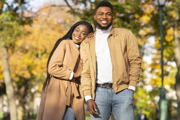 Mutlu Afro-Amerikan çifti, sonbahar parkında birlikte poz veriyor.