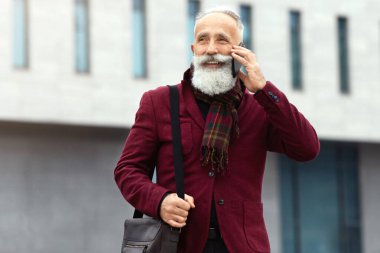 Ofisten eve dönerken cep telefonuyla konuşan, iş konuşan, bordo takım giyen, deri çanta taşıyan, fotokopi çeken, uzun sakallı, şık bir kıdemli adam.