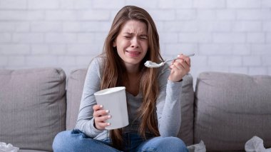 Duygusal yeme konsepti. Stresli milenyum hanımı kanepesinde dondurma kovasıyla ağlıyor, ilişki sorunu yaşıyor ya da hüzünlü bir film izliyor, kendini yalnız ve depresif hissediyor.