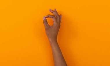 Onaylama konsepti. Siyah kadın eli, turuncu arkaplanı fotokopi alanı ile işaretliyor..