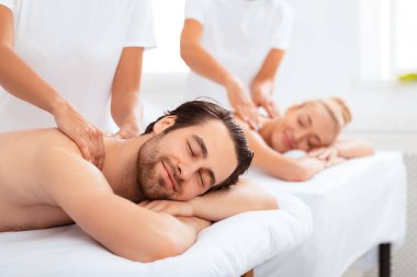 Vücut Rahatlaması. Eşler, kapalı gözlerle Spa Salonu 'nda karın üstü uzanarak boyun ve sırt masajı yaptırıyor. Çift Masaj Terapisi Konsepti. Seçici Odaklanma