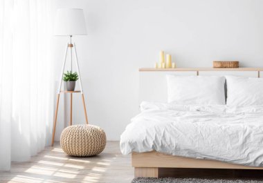 Yumuşak çift kişilik yatak, çiçekli lamba, aksesuarlı mobilyalar, beyaz arka planda perdeli pencere, boş alan. İskandinav tarzı rahat bir daire, sabahları minimalist yatak odası.