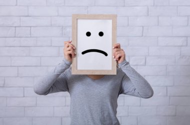 Depresyon, üzüntü, olumsuz duygu konsepti. Yüzünün önünde hüzünlü bir ifade olan çerçeveyi tutan genç bir kadın. Karamsarlık, yalnızlık, keder ve hüsranı ifade eden bin yıllık bir kadın.