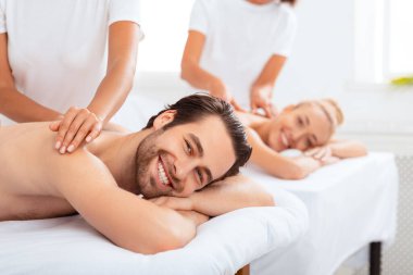 Çift Masaj Konsepti. Neşeli erkek arkadaş ve kız arkadaş, masajcılar boyunlarına masaj yaparken ve Spa Resort 'ta uzanıp eğleniyorlar. Romantik Rahatlama ve Güzellik Tedavisi Konsepti.