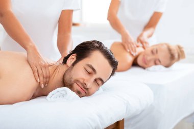 Spa tatili. Hoşnut eşler, lüks güzellik salonundaki yataklarda uzanırken, gözleri kapalı bir şekilde boyun masajının tadını çıkarıyorlar. Masör Vücut Masajı, Çiftler Masaj Terapisi. Seçici Odaklanma