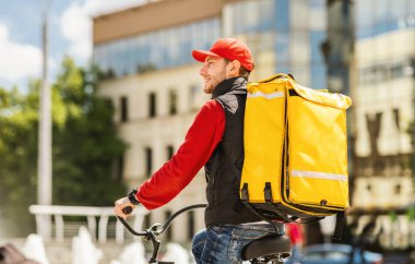 Kurye adam şehirde bisikletle yemek dağıtımı yapıyor, yemek dağıtım şirketinde çalışıyor. Metin için Boş Alan