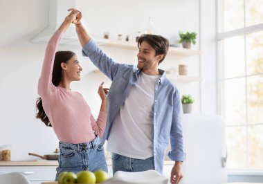 Mutlu ve çekici genç karı koca dans ediyor ve mutfak içinde birlikte eğleniyorlar, boş alanda. Çiftler hafta sonları ve boş zamanlarında kendi evlerinde romantik randevuların keyfini çıkarırlar.