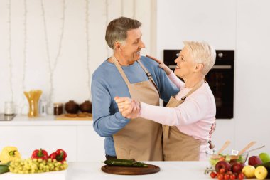 Modern mutfakta dans eden, akşam yemeği hazırlayan ve hafta sonları evde eğlenen neşeli yaşlı çift. Yaşlı Aile, Emeklilik Mutluluğu ve İlişki Yaşlılık Konsepti