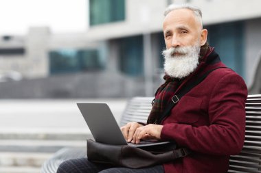 Modern büyükbaba sokakta bankta otururken dizüstü bilgisayar kullanır, klavyeye yazar ve kameraya bakar, roman yazar ya da emeklilik sırasında uzaktan bir işe sahip olur, boş alan