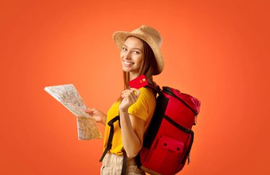 Sarı arka planda kredi kartı tutan kız sırt çantalı, seyahat zamanı.