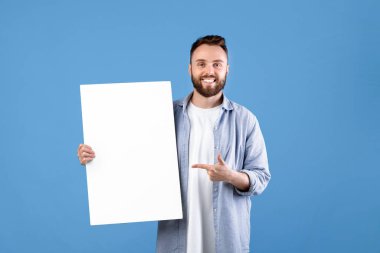 Reklam panosu reklamı. Gülümseyen genç adamın portresi boş beyaz posteri gösteriyor. Tasarımın için yer var. Mutlu milenyum insanları boş pankart şablonu sergiliyor