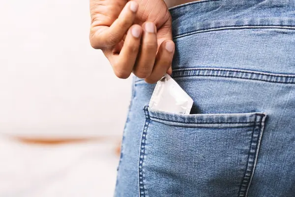 Emniyet seks konsepti. Tanınmayan siyah adam alarak prezervatif kot arka cebinden, kopya alanı