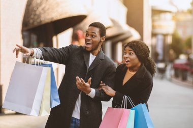 Omg, Kara Cuma 'da son satış. Şaşırmış ve heyecanlanmış bin yıllık Afro-Amerikan erkek ve kadın dükkanın vitrininde beliriyor ve alışveriş merkezinin yakınında bir sürü renkli alışveriş torbası tutuyor.