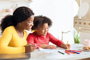 Mutlu siyah anne ve tatlı küçük kızı mutfak masasında bir araya geliyor, Afrikalı Amerikalı anneyi seviyor çocuğuyla birlikte gelişim faaliyetleri yapıyor, evde boş zamanların keyfini çıkarıyor,