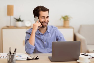 Gladful Man telefonda konuşuyor. İnternette bilgisayarda çalışıyor. Modern ofiste masasında oturuyor. Serbest Çalışan Adam içeride cep telefonuyla konuşuyor. Modern Mobil İletişim Konsepti