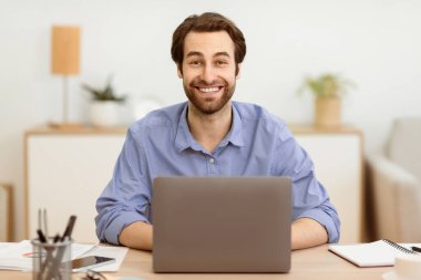 Bilgisayarın başındaki heyecanlı iş adamı. İnternette çalışıyor. İçişleri Bakanlığı 'ndaki masada oturan kameraya gülümsüyor. Uzak Serbest Çalışma, Mesafe İşi ve Başarılı Girişimcilik Kariyeri