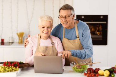 Yaşlı Evli Çiftler İnternette Laptop Tarama Tarifleri Kullanarak Birlikte Akşam Yemeğini Hazırlıyor Modern Mutfakta Birlikte Bekliyorlar. Mutlu Emekliler ve Emekliler Hobisi.