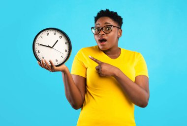 Son teslim tarihi, zaman doldu. Mavi Stüdyo 'nun arka planında duran, kameraya bakan, büyük boy Afrikalı Kadın Saat Pozisyonu. Geç kalan siyahi kadın şok oldu. Zaman Gıdıklama Kavramı