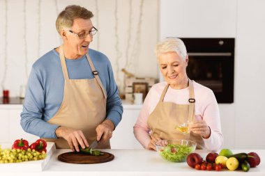 Son sınıf çifti, modern mutfaklarda salata yaparak yemek hazırlıyor. Olgun eşler evde birlikte yemek hazırlıyor. Emeklilik Yaşam Tarzı ve Hobileri