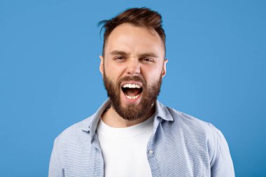Öfkeli sakallı adam öfkeyle bağırıyor, mavi stüdyo geçmişi üzerine saldırganlığını ifade ediyor. Duygusal milenyum adamı bağırıyor, öfkeli ya da sinirli hissediyor. Negatif insan duyguları konsepti