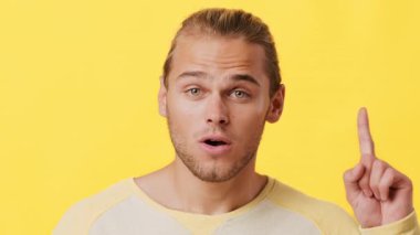 Afrika ve Kafkas özelliklerinin bir karışımına sahip genç bir adam kendinden emin bir şekilde gülümsüyor, önemli bir düşünceyi paylaşıyormuş gibi parmağını kaldırıyor..