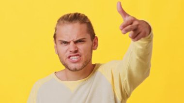 Açık renk saçlı ve kendine güveni olan genç bir adam rahat bir gömlek giyerken şakacı hareketler yapar. İfadesi canlandırılmış, bir neşe ve canlılık hissi veriyor..