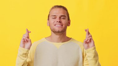 Afrika ve Kafkas özelliklerinin karışımından oluşan neşeli genç bir adam canlı sarı bir zemin üzerinde duruyor. Gözlerini kapar ve parmaklarını çapraz yapar, iyimserliğini ve heyecanını ifade eder..