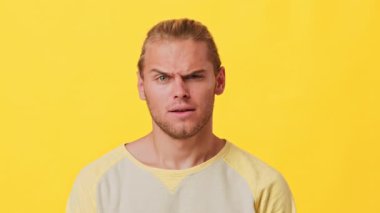 Afrika ve Kafkas mirasının bir karışımı ile neşeli bir genç adam yaygın bir şekilde gülümsüyor. Uzun saçları var ve rahat bir gömlek giyiyor. Parlak sarı arka plan onun neşeli ifadesini arttırır..