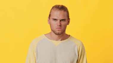 Afrika ve Kafkas özelliklerine sahip bir adam parlak sarı bir arkaplan önünde ciddi bir ifade sergiler. Gündelik, açık renkli bir kazak giyiyor, yoğun bir ruh hali içinde..