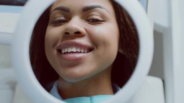 Afro-Amerikalı kadın tedavi gördükten sonra dişçi kliniğinde aynayla etkileşime giriyor.