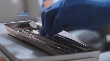 Bir Afrikalı Amerikalı dişçi modern bir diş kliniğinde hasta danışmanlığı için hazırlanırken diş aletlerini bir tepside organize eder. Alan, profesyonel bir sağlık ortamını yansıtıyor.