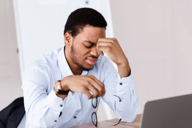 Yorgun Afrika kökenli Amerikalı menajer ya da resmi gömlekli CEO 'su tükenmiş, dizüstü bilgisayarın önünde oturmuş, gözlerini ovuşturuyor, yaratıcı çözümler arıyor, fikir yoksunluğu, kopyalama alanı.